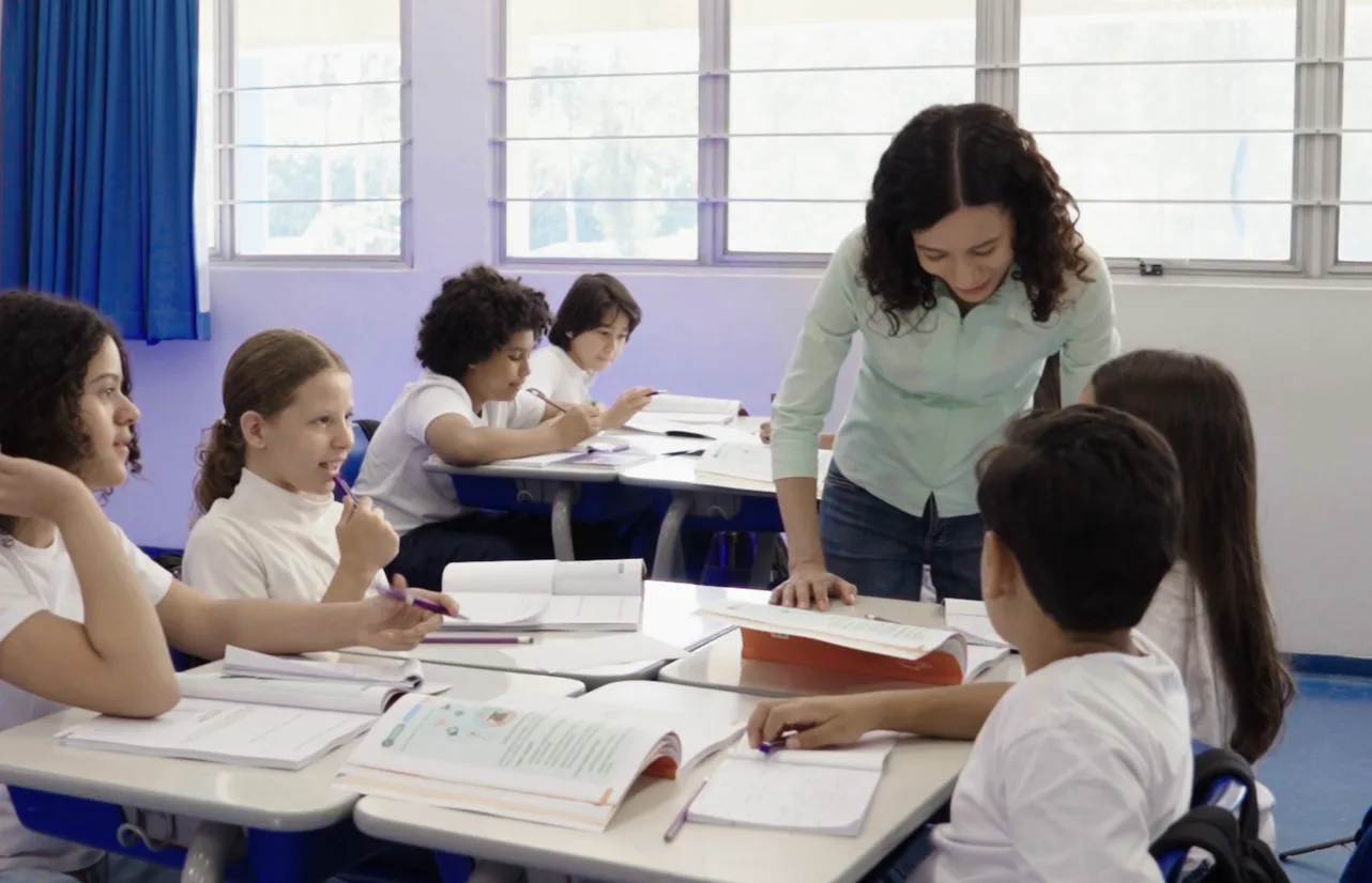 Professora acompanhando estudantes em sala de aula, cena do vídeo institucional da Verbum